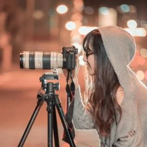femme utilisant un appareil photo professionnel sur un trépier